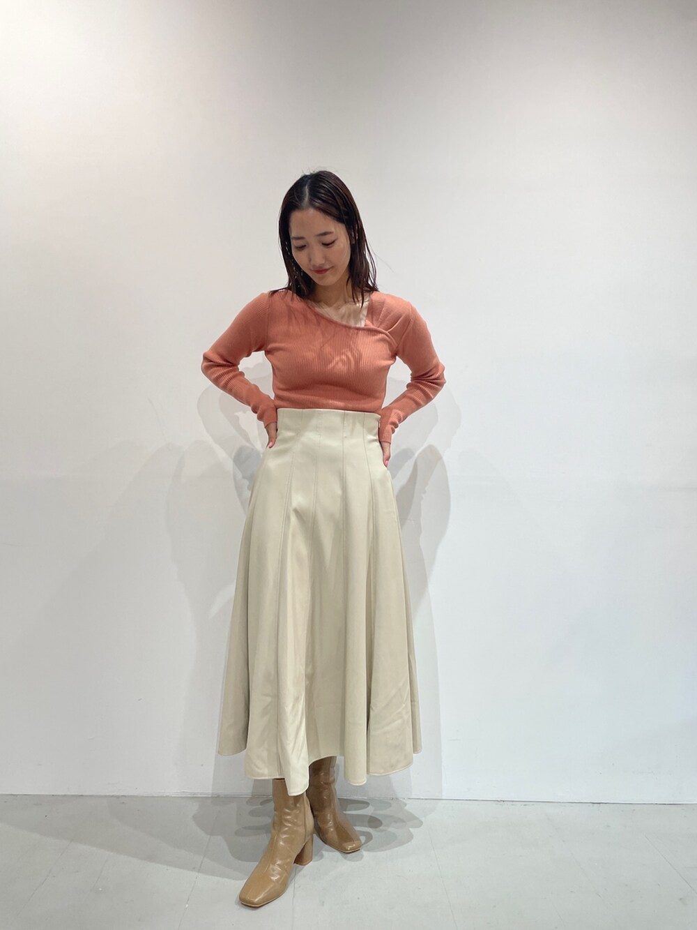 ホワイト系のスカート、ベージュ系のブーツ、オレンジ系のニット/セーターを着用したレディースの夏コーディネートの8枚目の写真