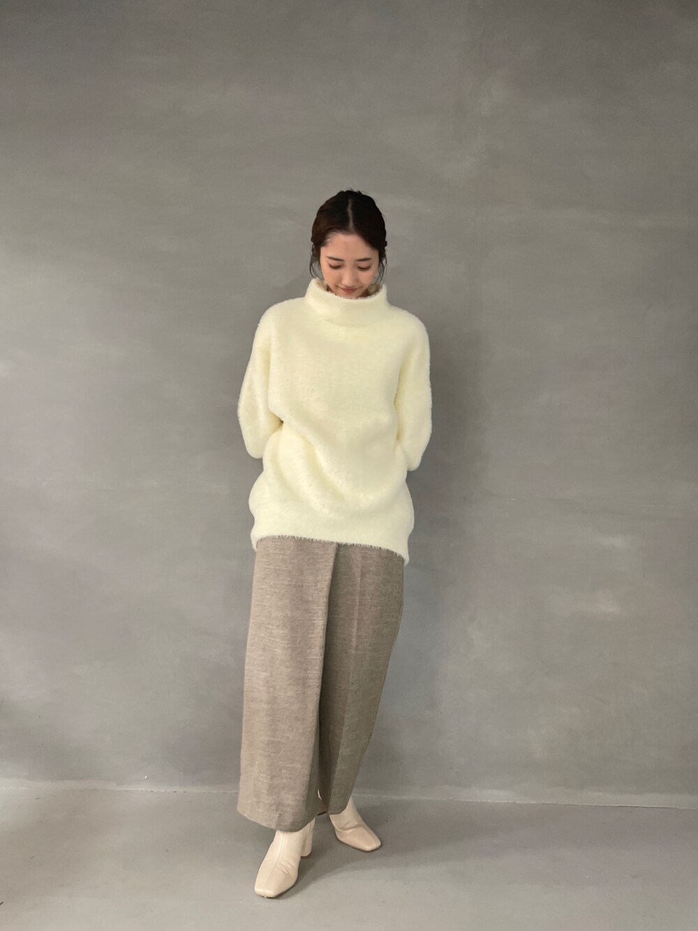 ホワイト系のニット/セーター、ベージュ系のその他パンツ、ホワイト系のブーツを着用したレディースの夏コーディネートの8枚目の写真