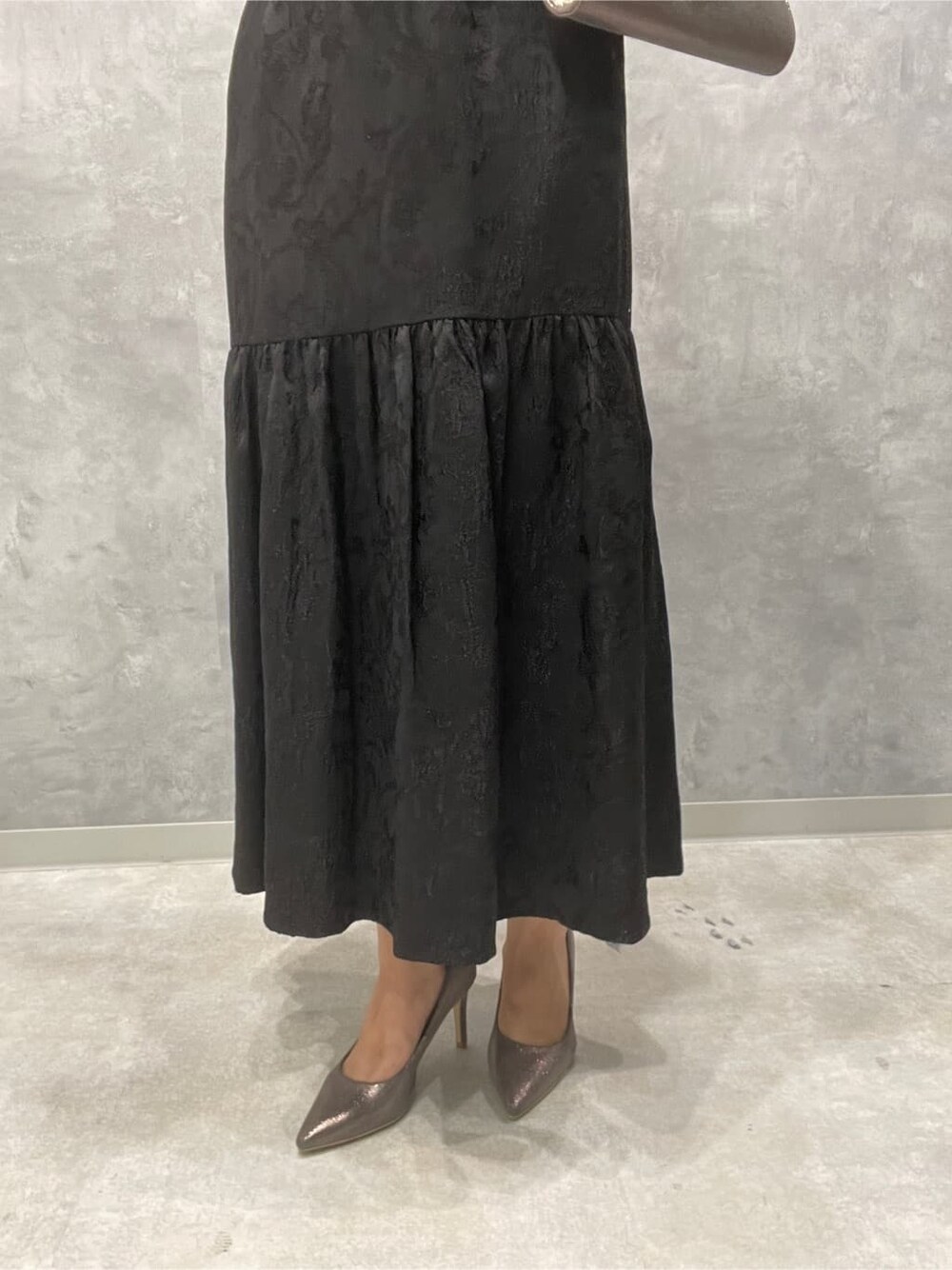 シルバー系のパンプス、シルバー系のクラッチバッグ、ブラック系のドレスを着用したレディースの夏コーディネートの9枚目の写真