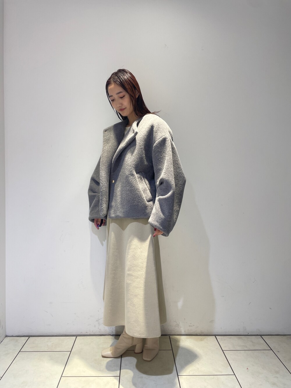 ホワイト系のニット/セーター、ホワイト系のジャンパースカート、ホワイト系のブーツを着用したレディースの秋コーディネートの7枚目の写真