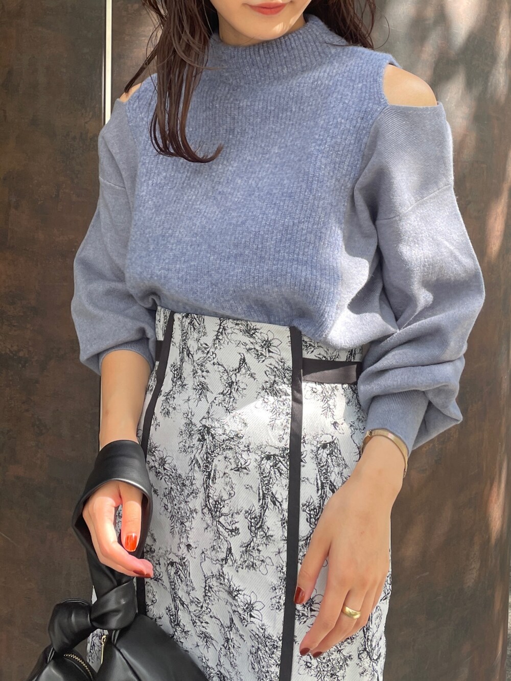 ブラック系のハンドバッグ、ブラック系のスカート、ブラック系のブーツを着用したレディースの秋コーディネートの6枚目の写真