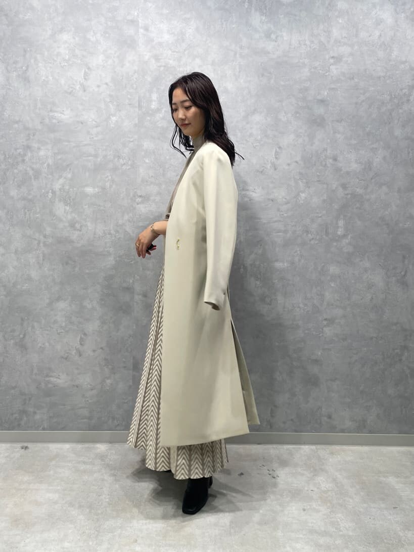 ホワイト系のノーカラーコート、ブラック系のブーツ、ベージュ系のワンピースを着用したレディースの秋コーディネートの9枚目の写真
