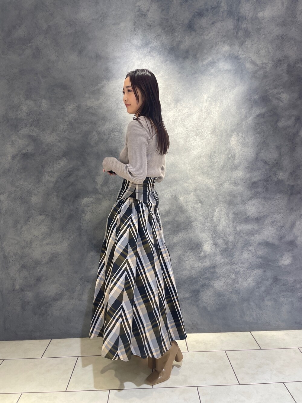 グレー系のニット/セーター、ベージュ系のブーツ、オレンジ系のスカートを着用したレディースの秋コーディネートの4枚目の写真