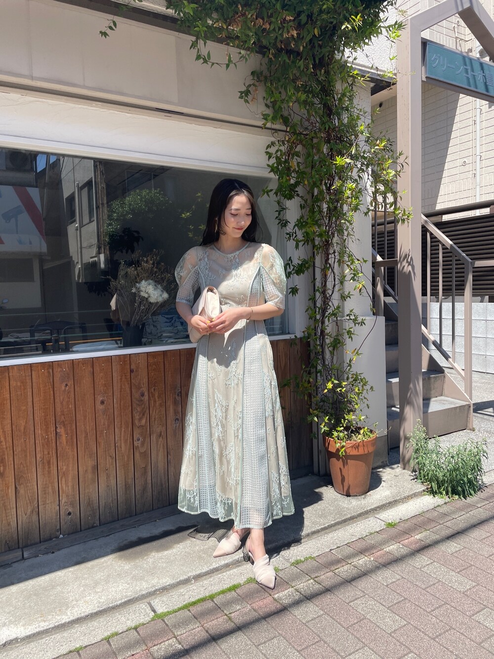 グリーン系のドレス、ベージュ系のハンドバッグ、ベージュ系のパンプスを着用したレディースの春コーディネートの3枚目の写真