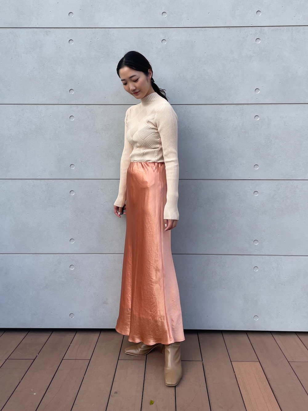 ホワイト系のニット/セーター、オレンジ系のスカート、ベージュ系のブーツを着用したレディースの冬コーディネートの4枚目の写真