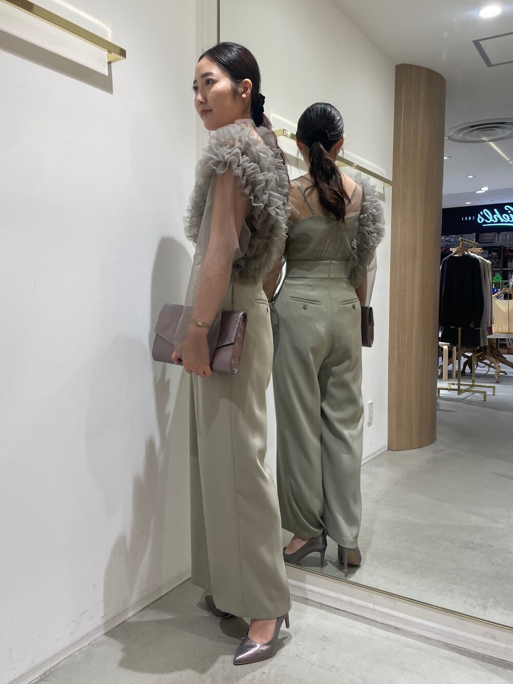 グリーン系のパンツドレス、シルバー系のハンドバッグ、シルバー系のパンプスを着用したレディースの冬コーディネートの5枚目の写真