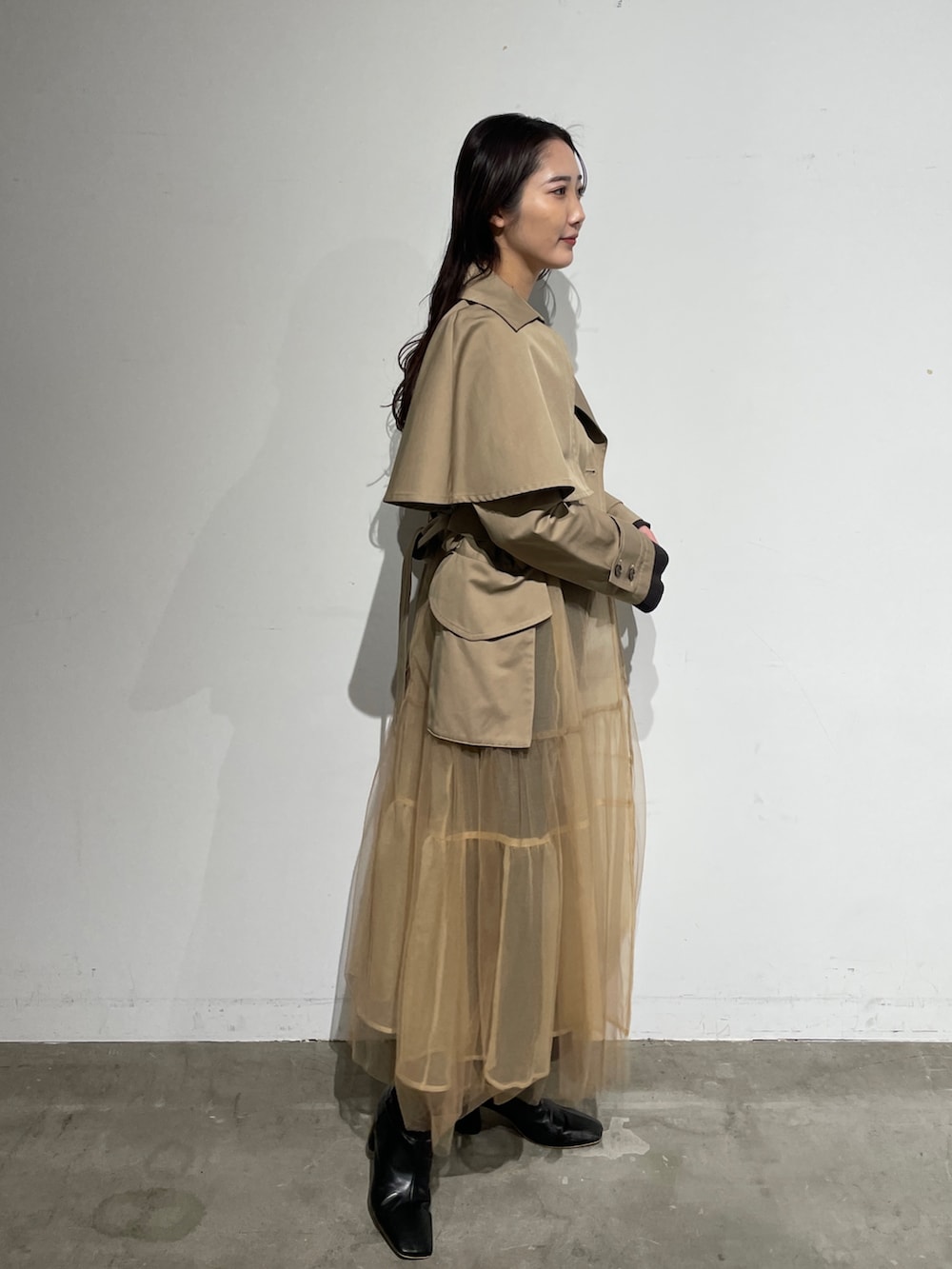 ブラック系のブーツ、グレー系のワンピース、ベージュ系のトレンチコートを着用したレディースの春コーディネートの4枚目の写真