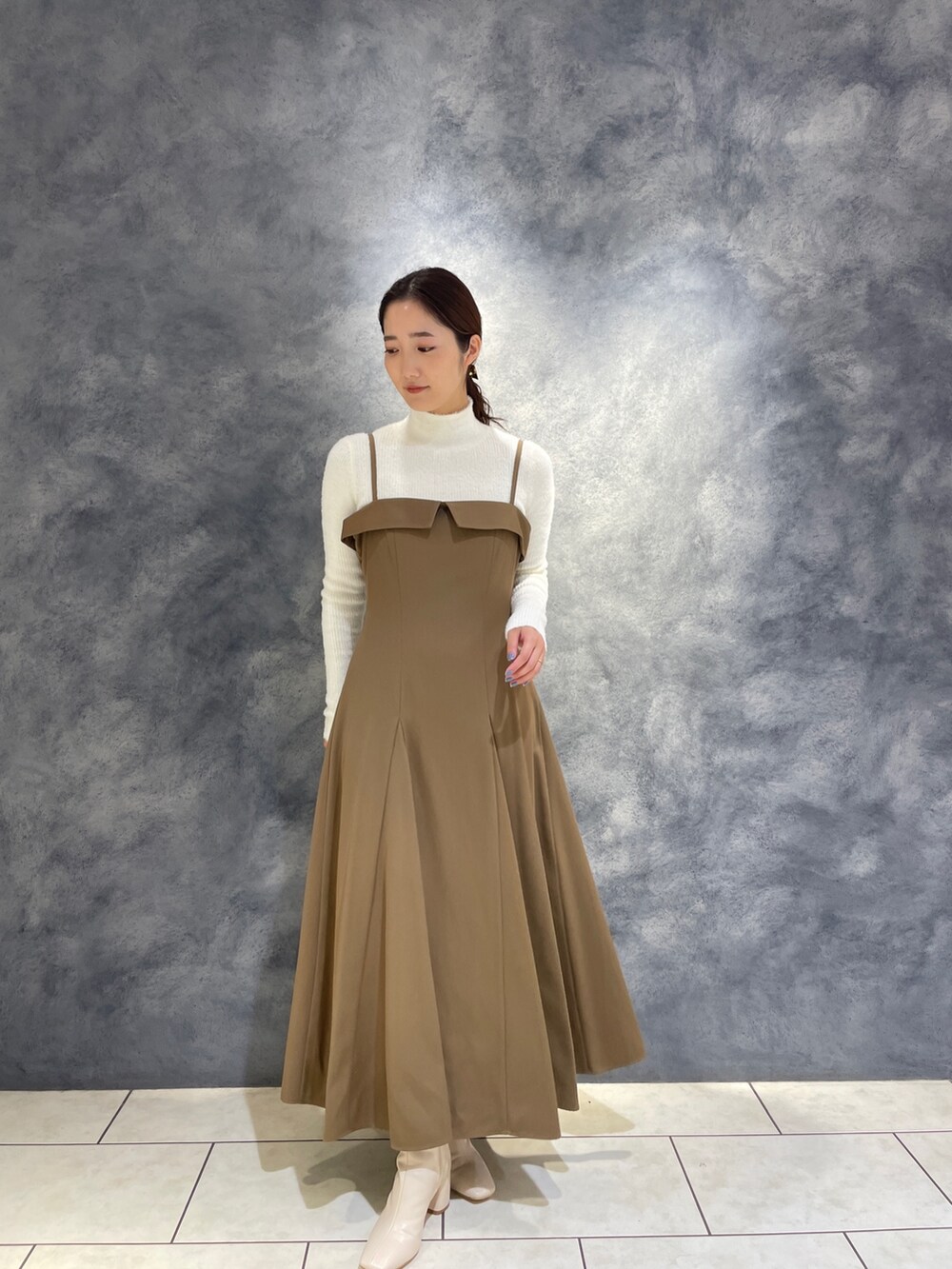 ベージュ系のワンピース、ホワイト系のニット/セーター、ホワイト系のブーツを着用したレディースの冬コーディネートの5枚目の写真