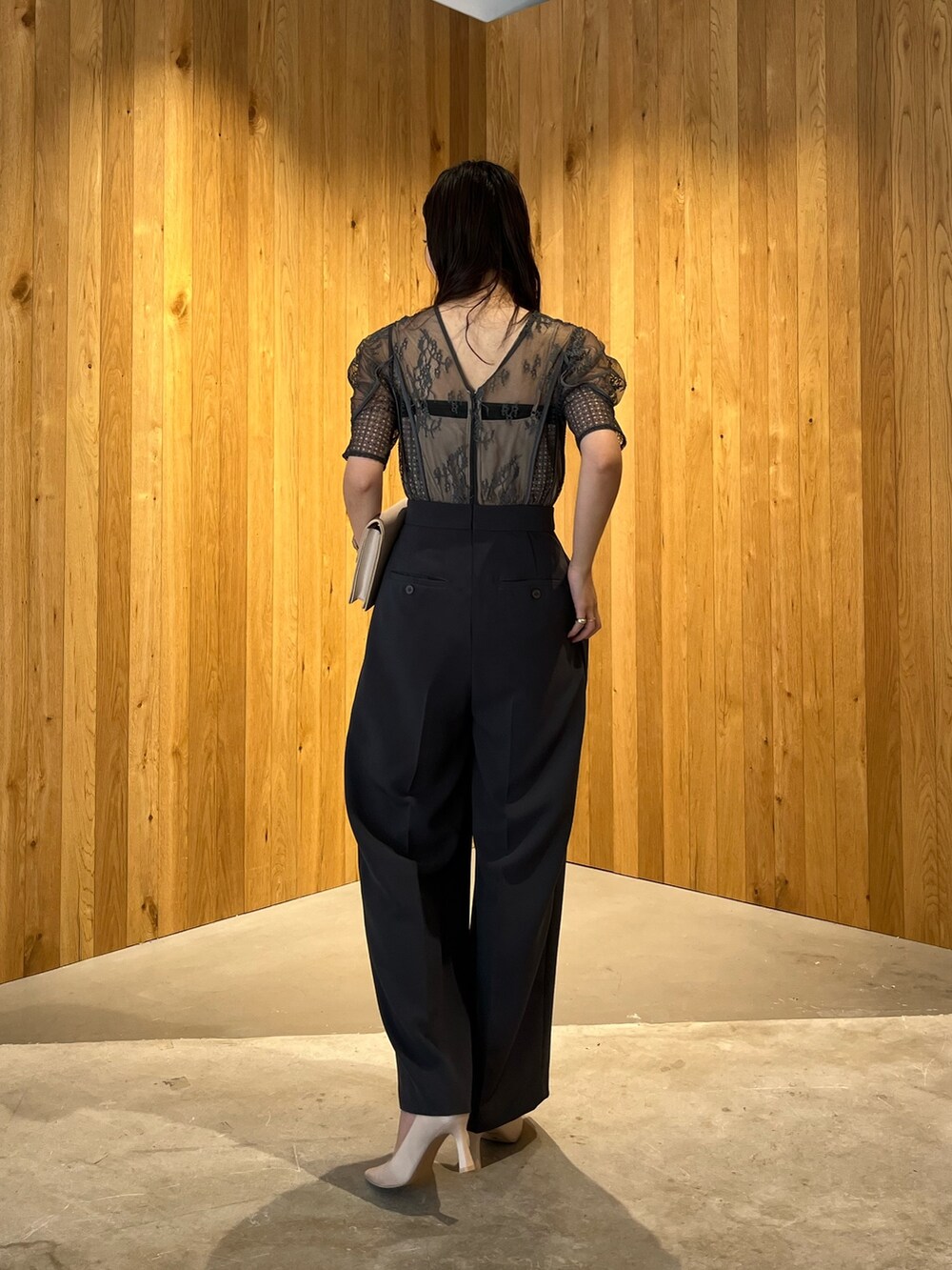 グレー系のパンツドレス、ベージュ系のクラッチバッグ、ベージュ系のパンプスを着用したレディースの冬コーディネートの4枚目の写真