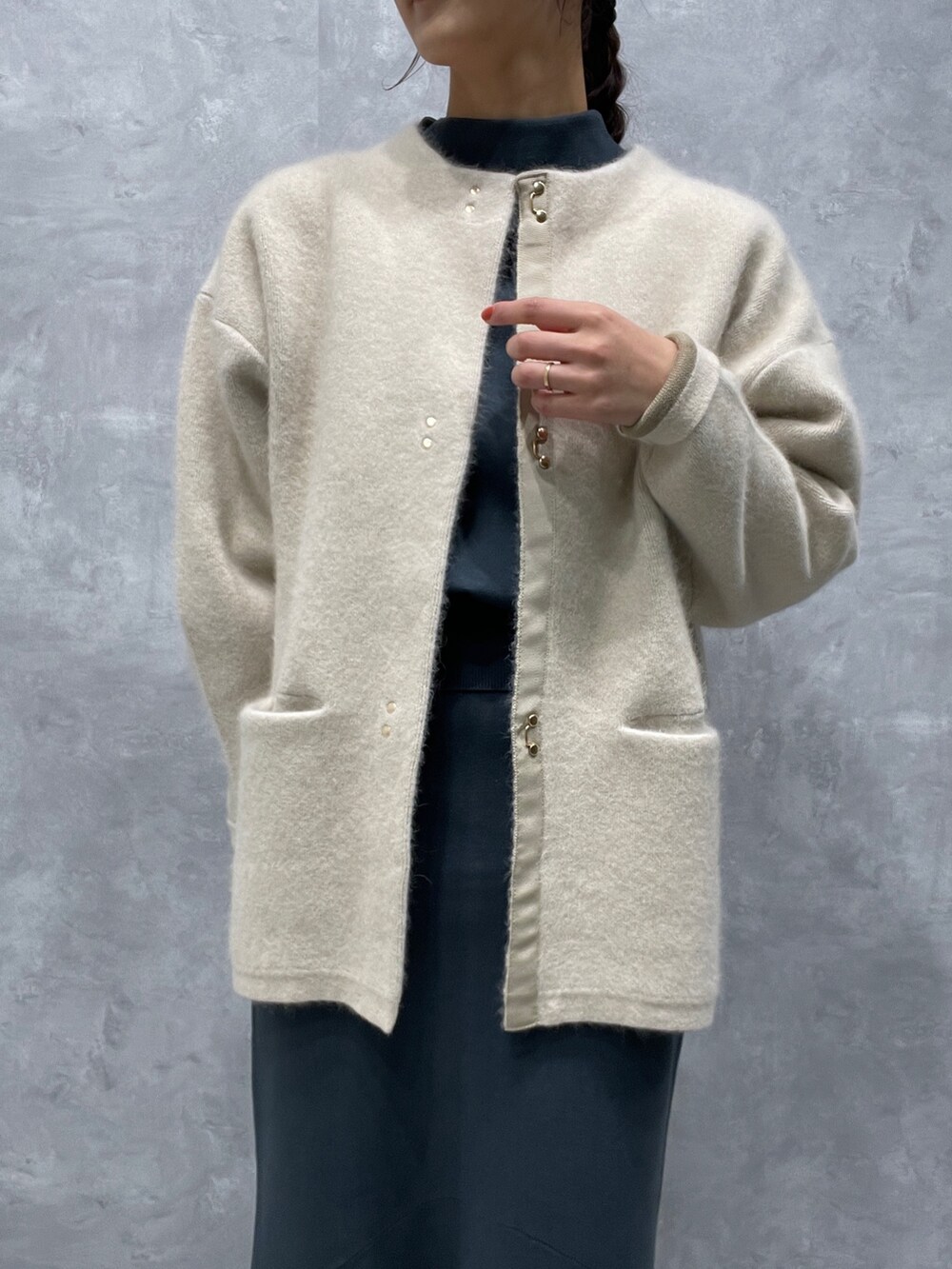 ホワイト系のカーディガン/ボレロ、グリーン系のニット/セーター、グリーン系のスカートを着用したレディースの冬コーディネートの3枚目の写真