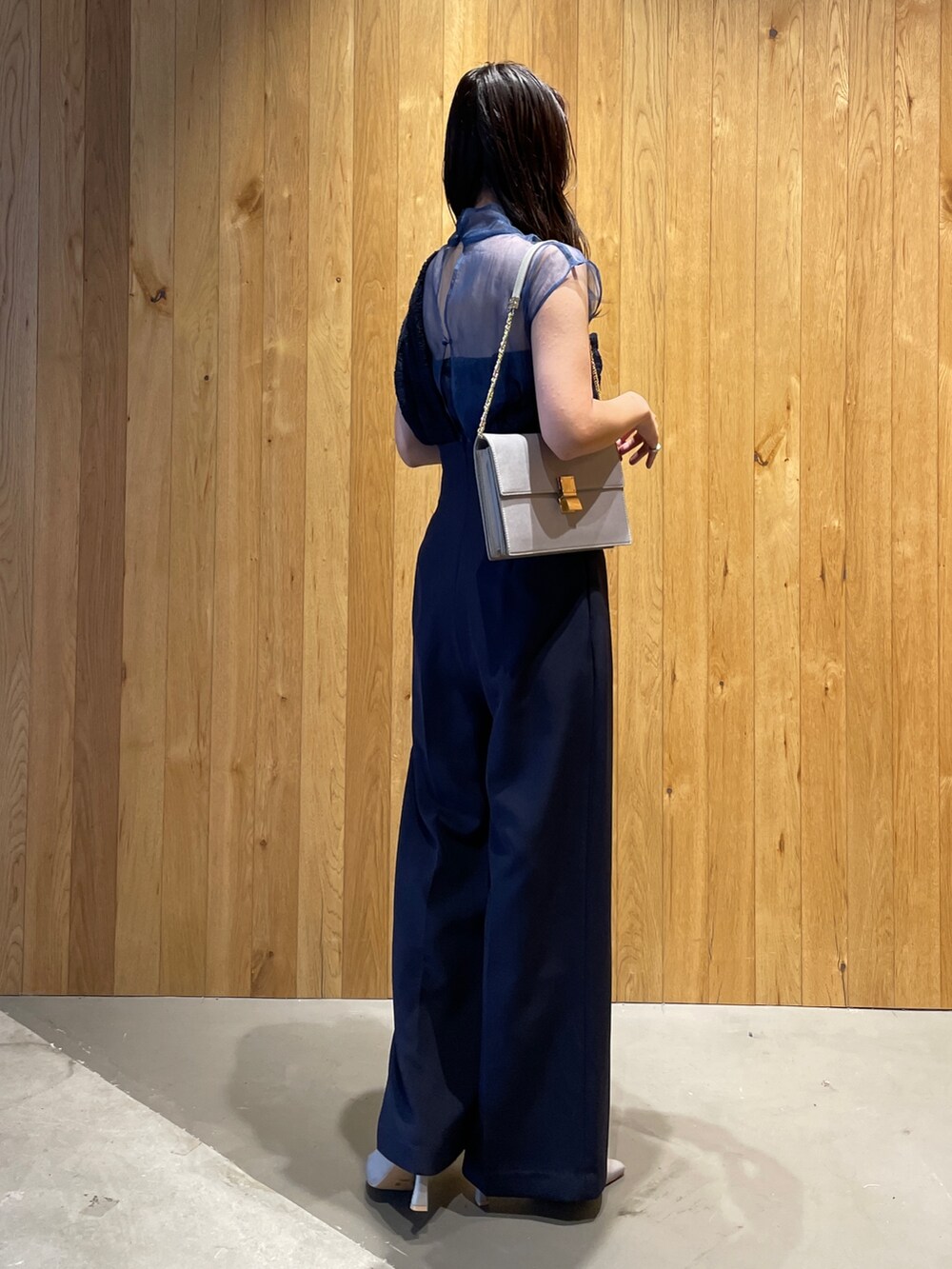 グレー系のクラッチバッグ、グレー系のパンプス、ブルー系のパンツドレスを着用したレディースの冬コーディネートの4枚目の写真