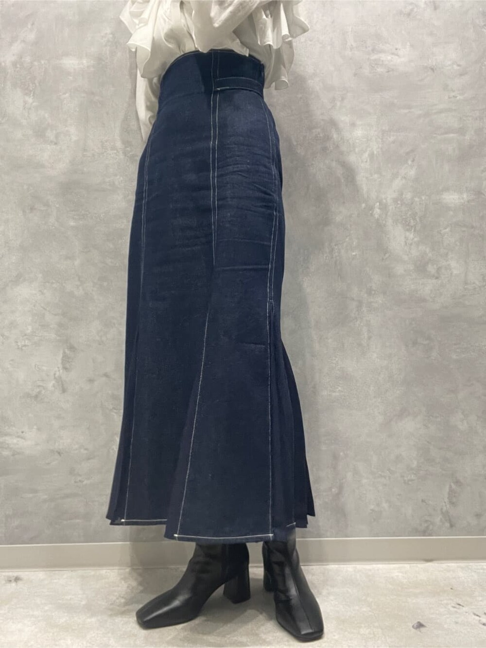 ブラック系のブーツ、ブルー系のスカート、ホワイト系のシャツ/ブラウスを着用したレディースの秋コーディネートの7枚目の写真