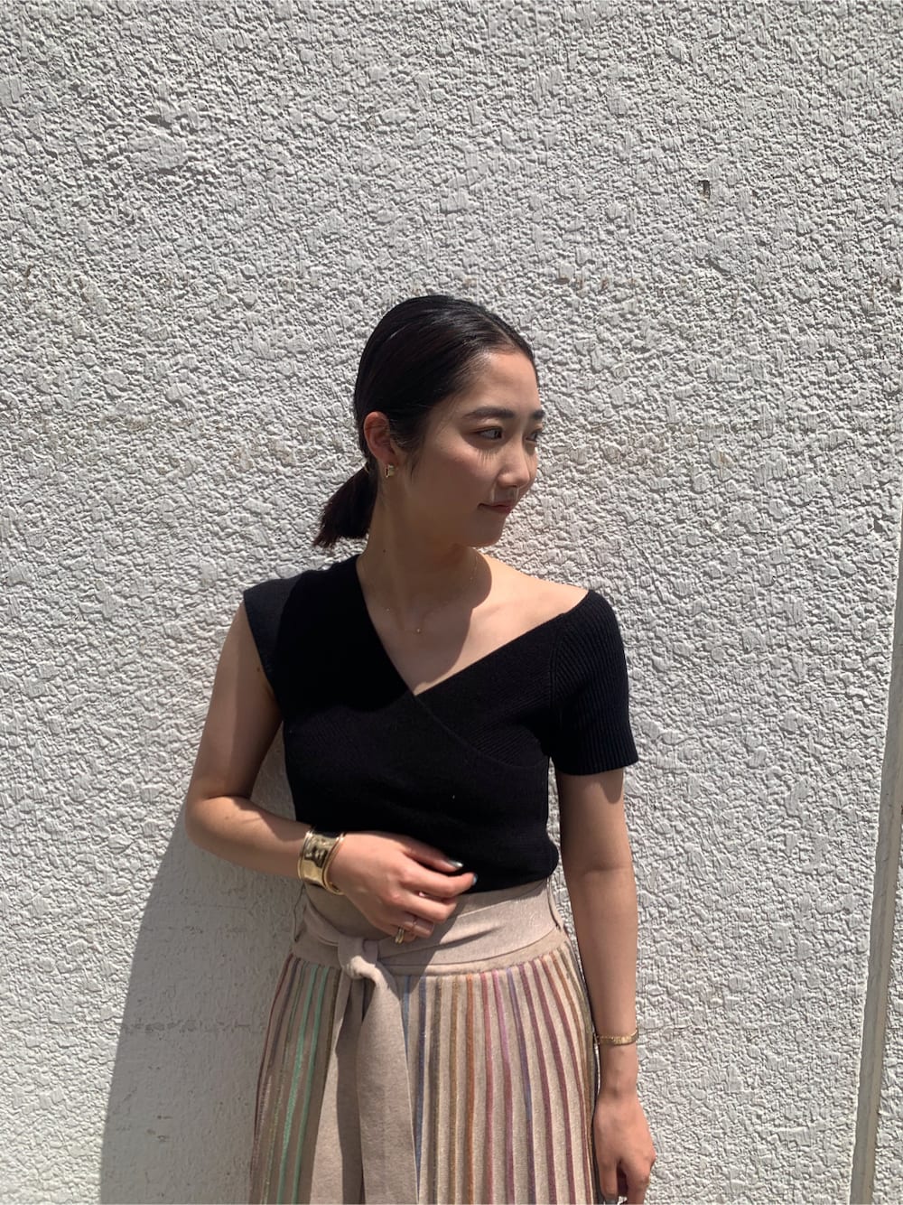 ベージュ系のスカート、ブラック系のニット/セーター、ゴールド系のバングル/リストバンドを着用したレディースの春コーディネートの3枚目の写真