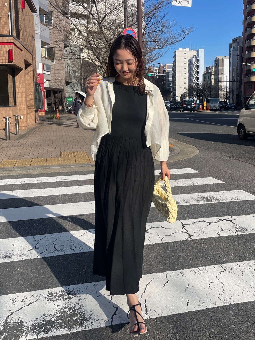 ブラック系のワンピース、ベージュ系のハンドバッグ、ブラック系のサンダルを着用したレディースの春コーディネートの4枚目の写真