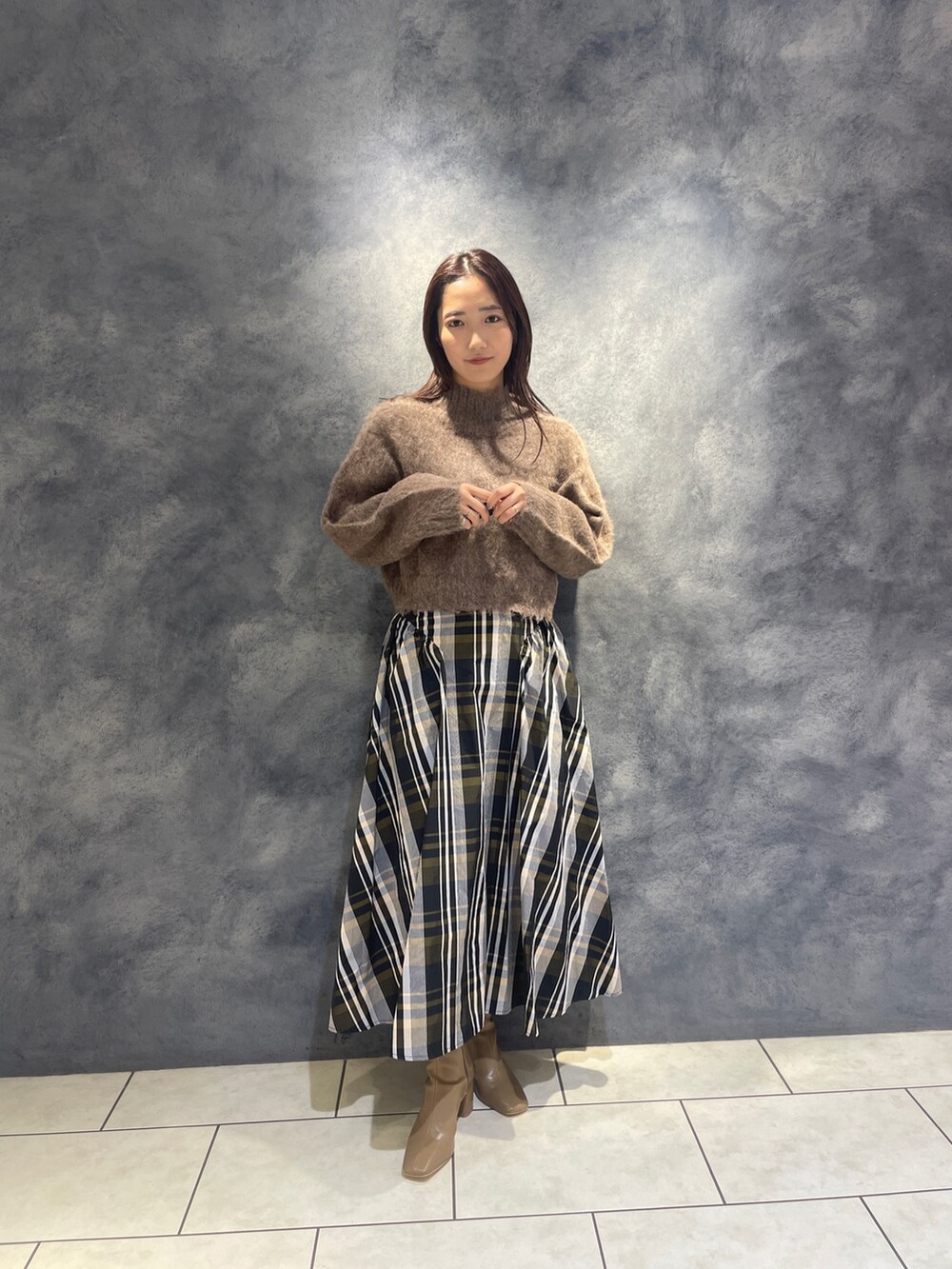 ブラウン系のニット/セーター、オレンジ系のスカート、ベージュ系のブーツを着用したレディースの秋コーディネートの4枚目の写真