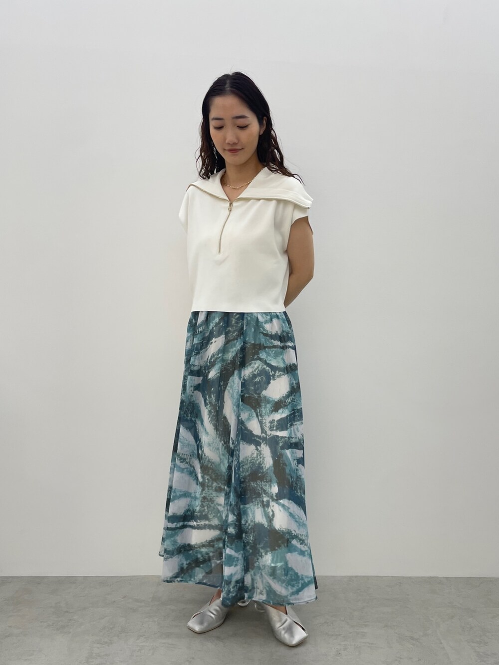 シルバー系のパンプス、ブルー系のスカート、ホワイト系のTシャツ/カットソーを着用したレディースの春コーディネートの2枚目の写真