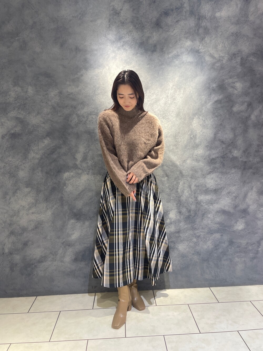 ブラウン系のニット/セーター、オレンジ系のスカート、ベージュ系のブーツを着用したレディースの秋コーディネートの3枚目の写真