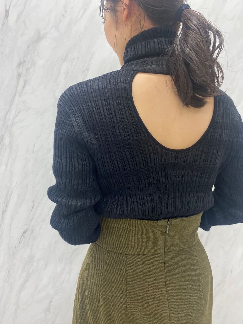 ベージュ系のスカート、ブラック系のニット/セーター、ブラック系のブーツを着用したレディースの夏コーディネートの9枚目の写真