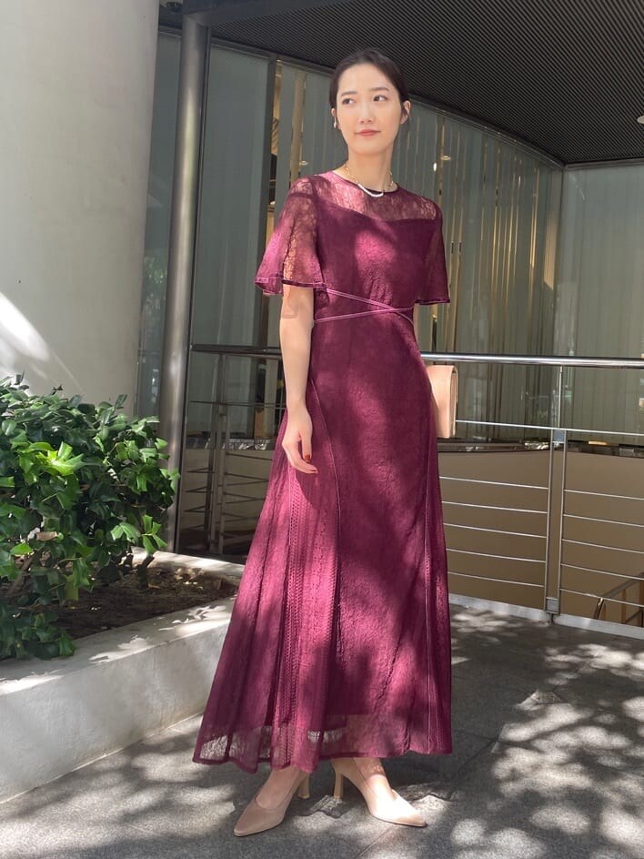 レッド系のドレス、ゴールド系のクラッチバッグ、ゴールド系のパンプスを着用したレディースの秋コーディネートの3枚目の写真