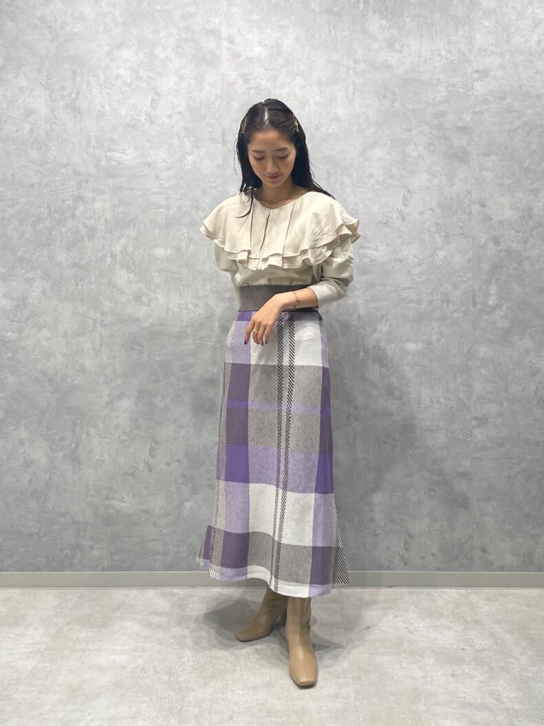 ベージュ系のブーツ、ホワイト系のニット/セーター、パープル系のスカートを着用したレディースの秋コーディネートの2枚目の写真