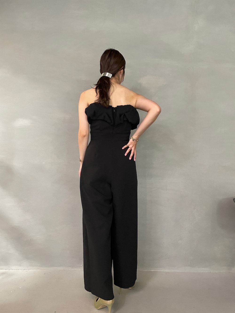 ゴールド系のパンプス、ブラック系のパンツドレス、シルバー系のチョーカーを着用したレディースの夏コーディネートの4枚目の写真