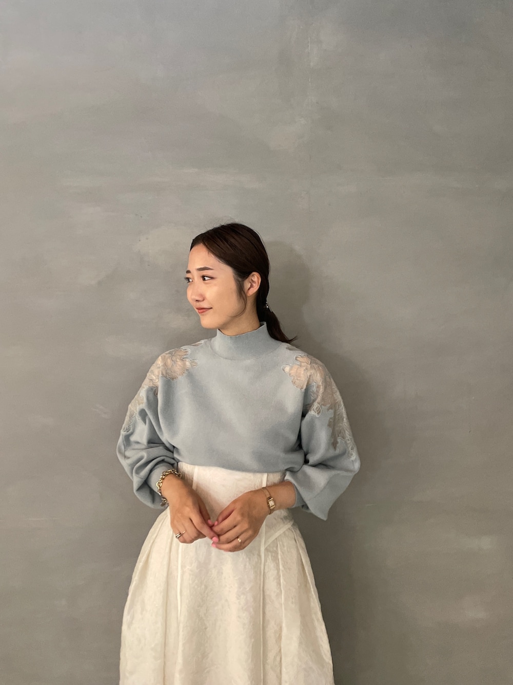 グレー系のニット/セーター、ホワイト系のスカート、ホワイト系のブーツを着用したレディースの夏コーディネートの6枚目の写真