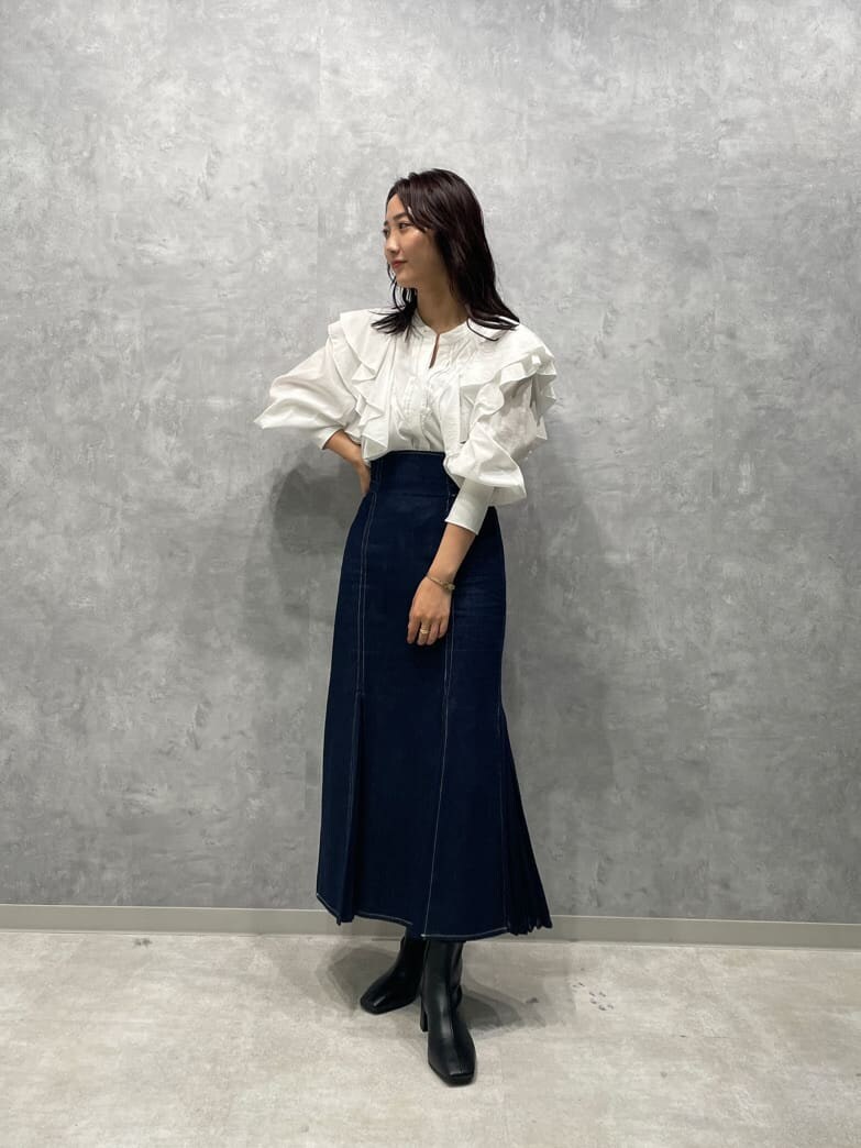 ブラック系のブーツ、ブルー系のスカート、ホワイト系のシャツ/ブラウスを着用したレディースの秋コーディネートの2枚目の写真