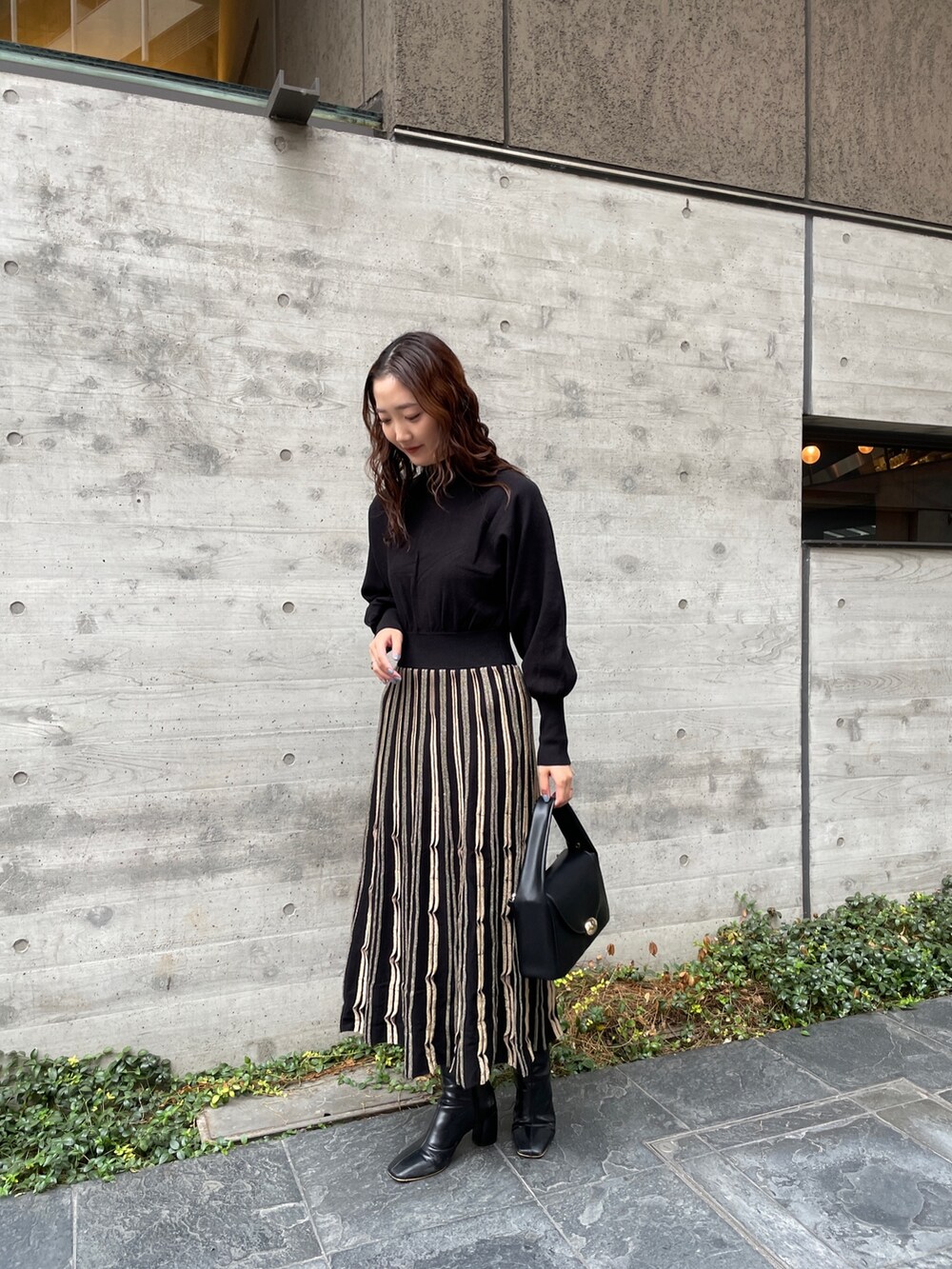 ブルー系のノーカラーコート、ブラック系のワンピース、ブラック系のブーツを着用したレディースの冬コーディネートの8枚目の写真