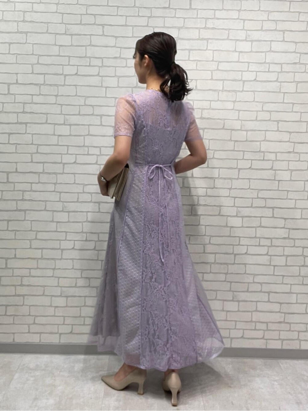 ベージュ系のパンプス、パープル系のドレス、ゴールド系のネックレスを着用したレディースの春コーディネートの3枚目の写真