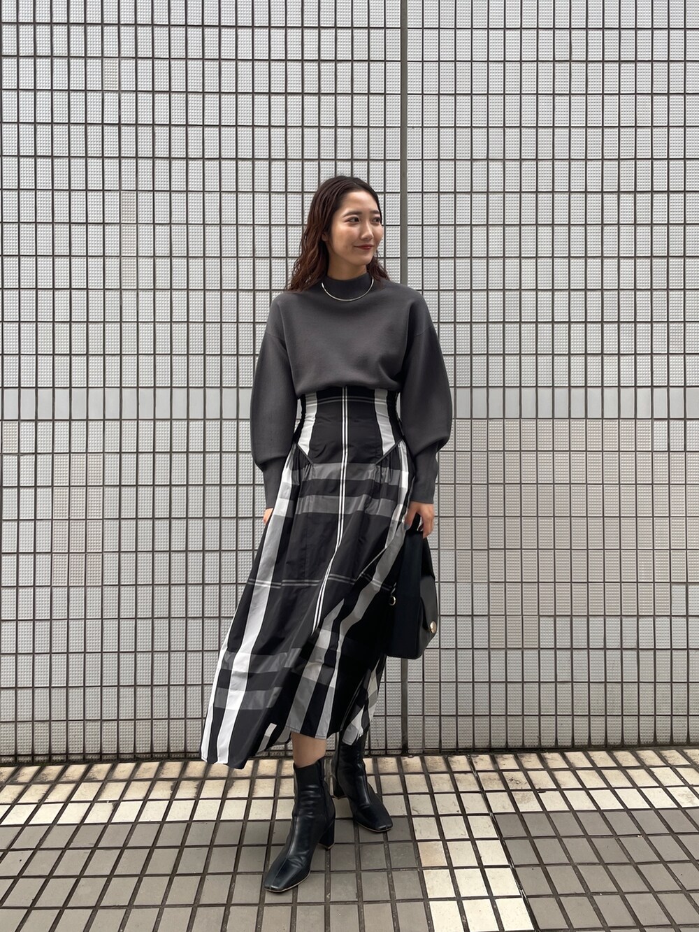 ブラック系のワンピース、ブラック系のブーツ、ブラック系のハンドバッグを着用したレディースの冬コーディネートの3枚目の写真