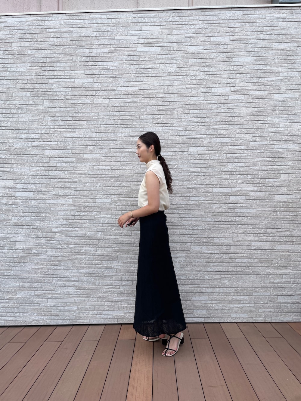 ブラック系のスカート、ホワイト系のTシャツ/カットソー、ブラック系のサンダルを着用したレディースの夏コーディネートの4枚目の写真