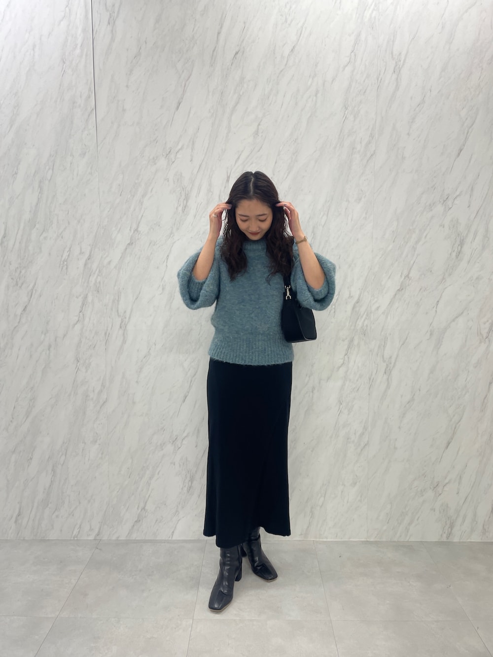 グリーン系のニット/セーター、ブラック系のブーツ、ブラック系のスカートを着用したレディースの冬コーディネートの4枚目の写真