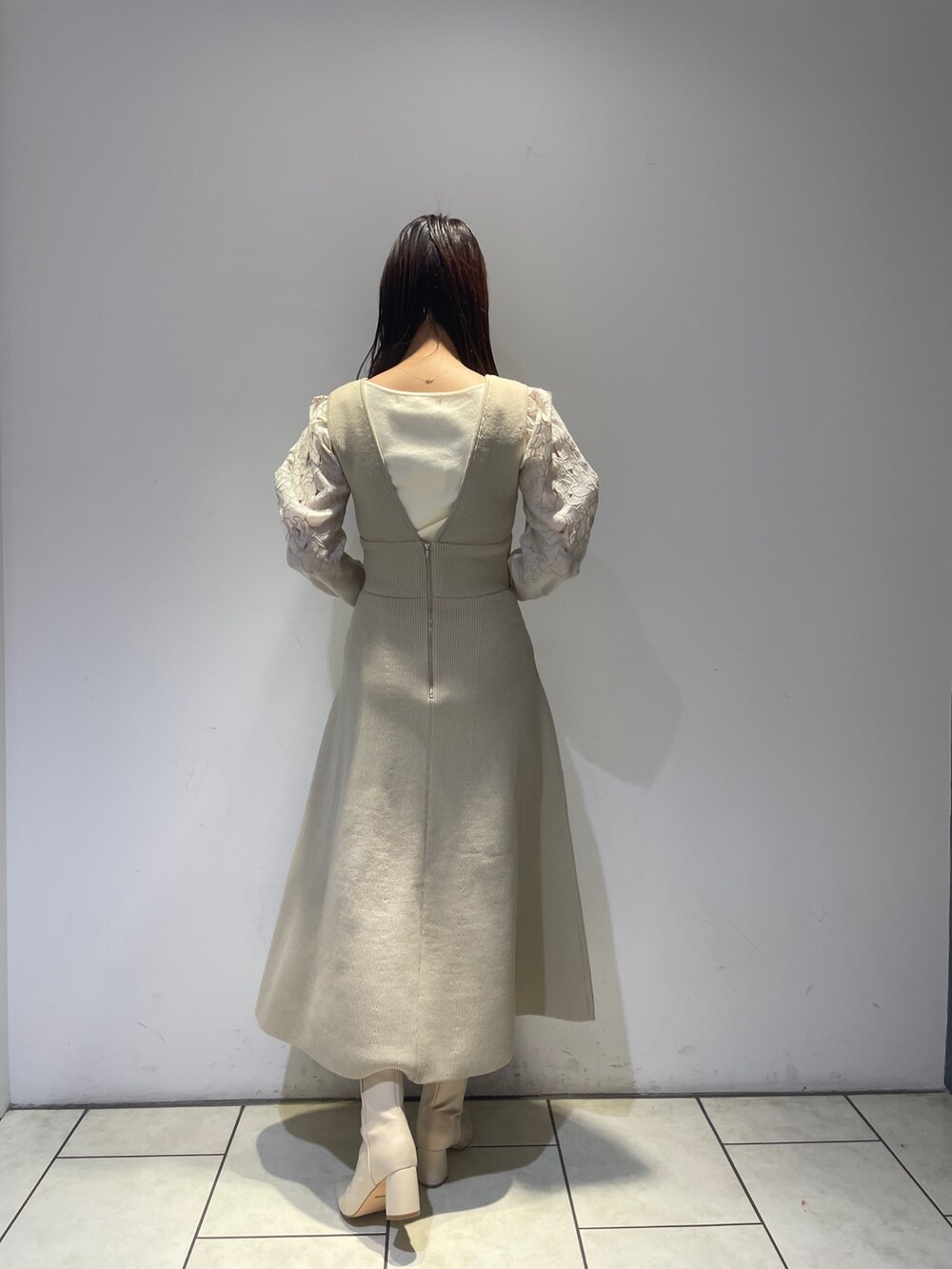 ホワイト系のニット/セーター、ホワイト系のジャンパースカート、ホワイト系のブーツを着用したレディースの秋コーディネートの5枚目の写真