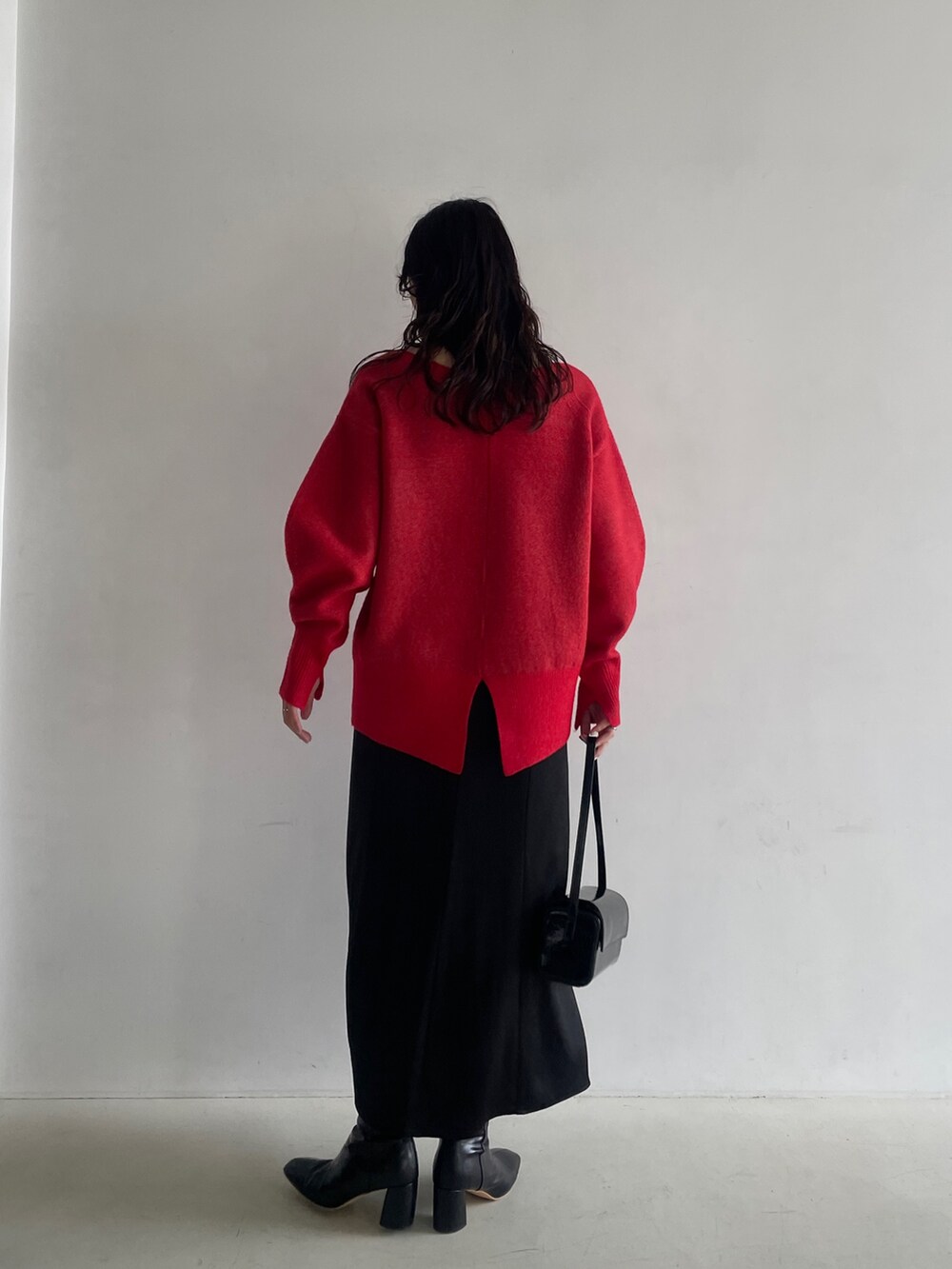 ブラック系のブーツ、ブラック系のスカート、レッド系のニット/セーターを着用したレディースの秋コーディネートの6枚目の写真