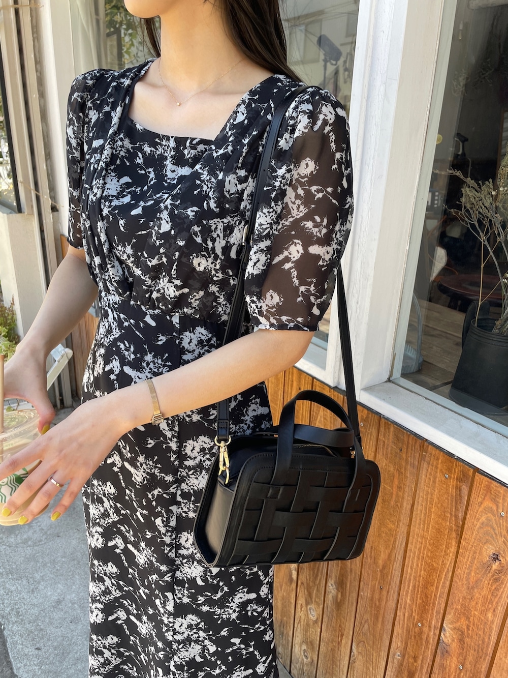 ブラック系のショルダーバッグ、ブラック系のワンピース、ブラック系のパンプスを着用したレディースの春コーディネートの6枚目の写真