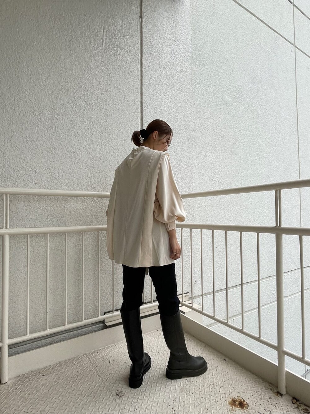 ブラック系のブーツ、ホワイト系のショルダーバッグ、ブルー系のデニムパンツを着用したレディースの秋コーディネートの5枚目の写真