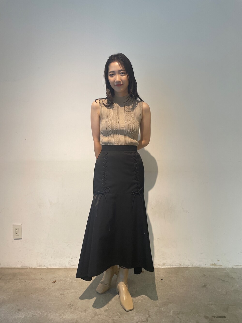 ベージュ系のニット/セーター、ベージュ系のブーツ、ブラック系のスカートを着用したレディースの夏コーディネートの3枚目の写真