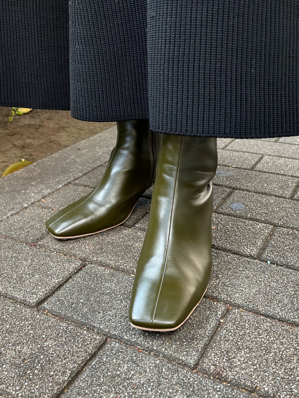 ブラック系のスカート、ブラック系のニット/セーター、グリーン系のブーツを着用したレディースの秋コーディネートの9枚目の写真