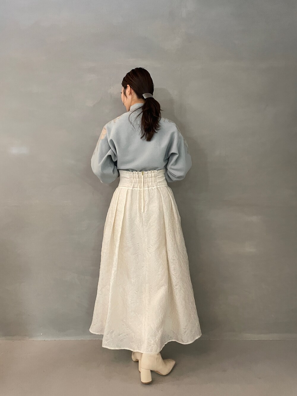 グレー系のニット/セーター、ホワイト系のスカート、ホワイト系のブーツを着用したレディースの夏コーディネートの5枚目の写真