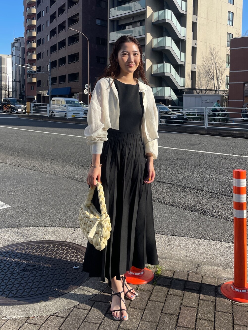 ブラック系のワンピース、ベージュ系のハンドバッグ、ブラック系のサンダルを着用したレディースの春コーディネートの3枚目の写真