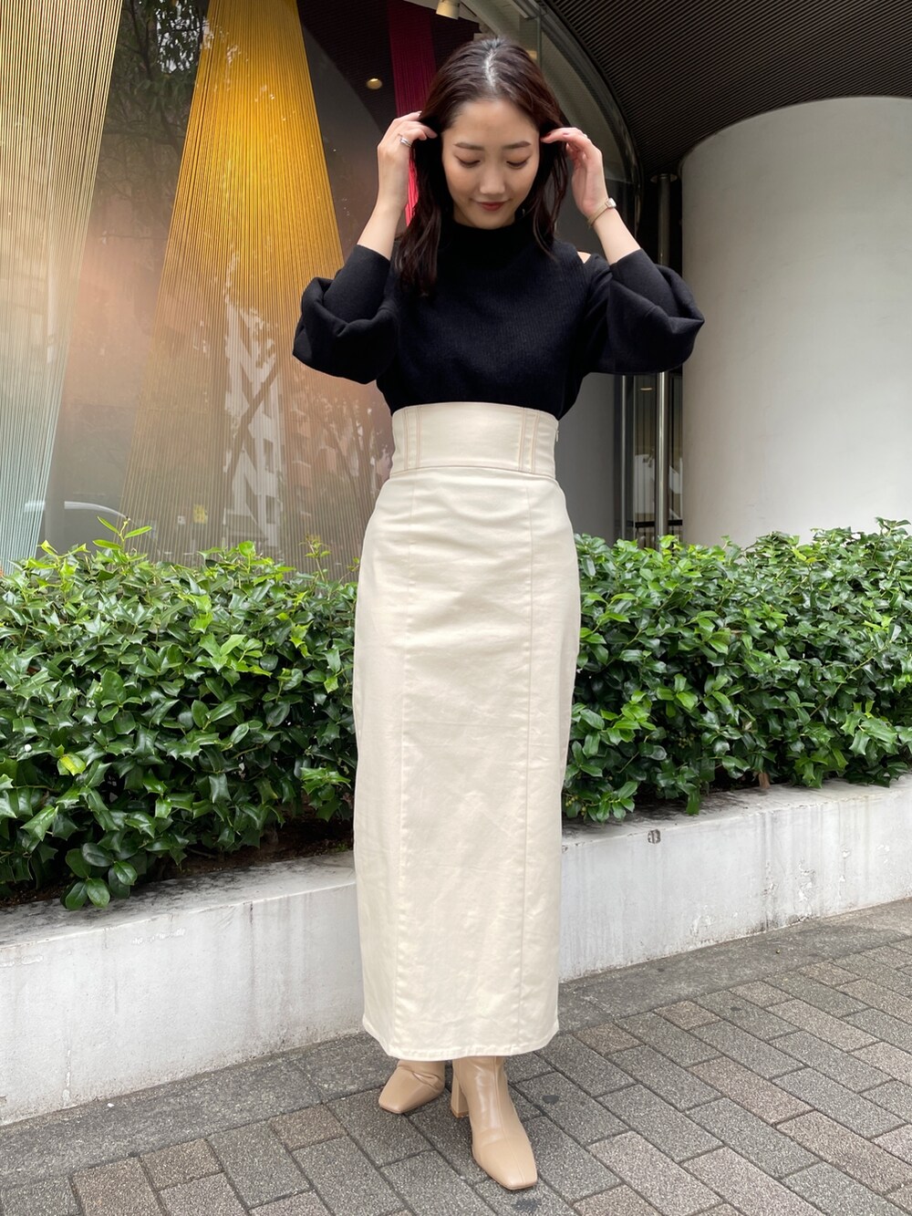 ベージュ系のブーツ、ブラック系のニット/セーター、ホワイト系のスカートを着用したレディースの秋コーディネートの3枚目の写真