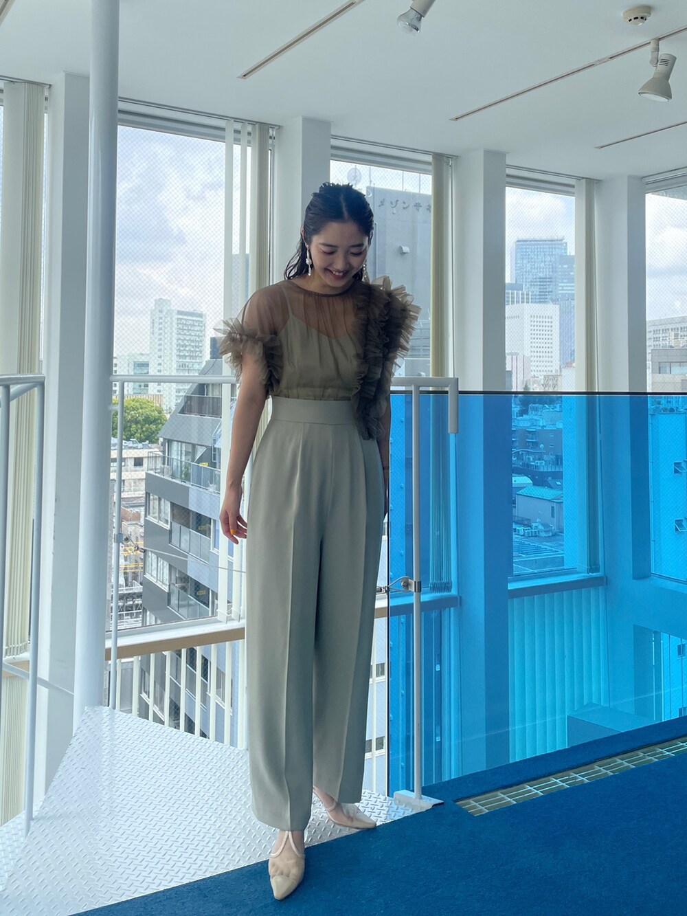 グリーン系のパンツドレス、ベージュ系のパンプスを着用したレディースの春コーディネートの2枚目の写真