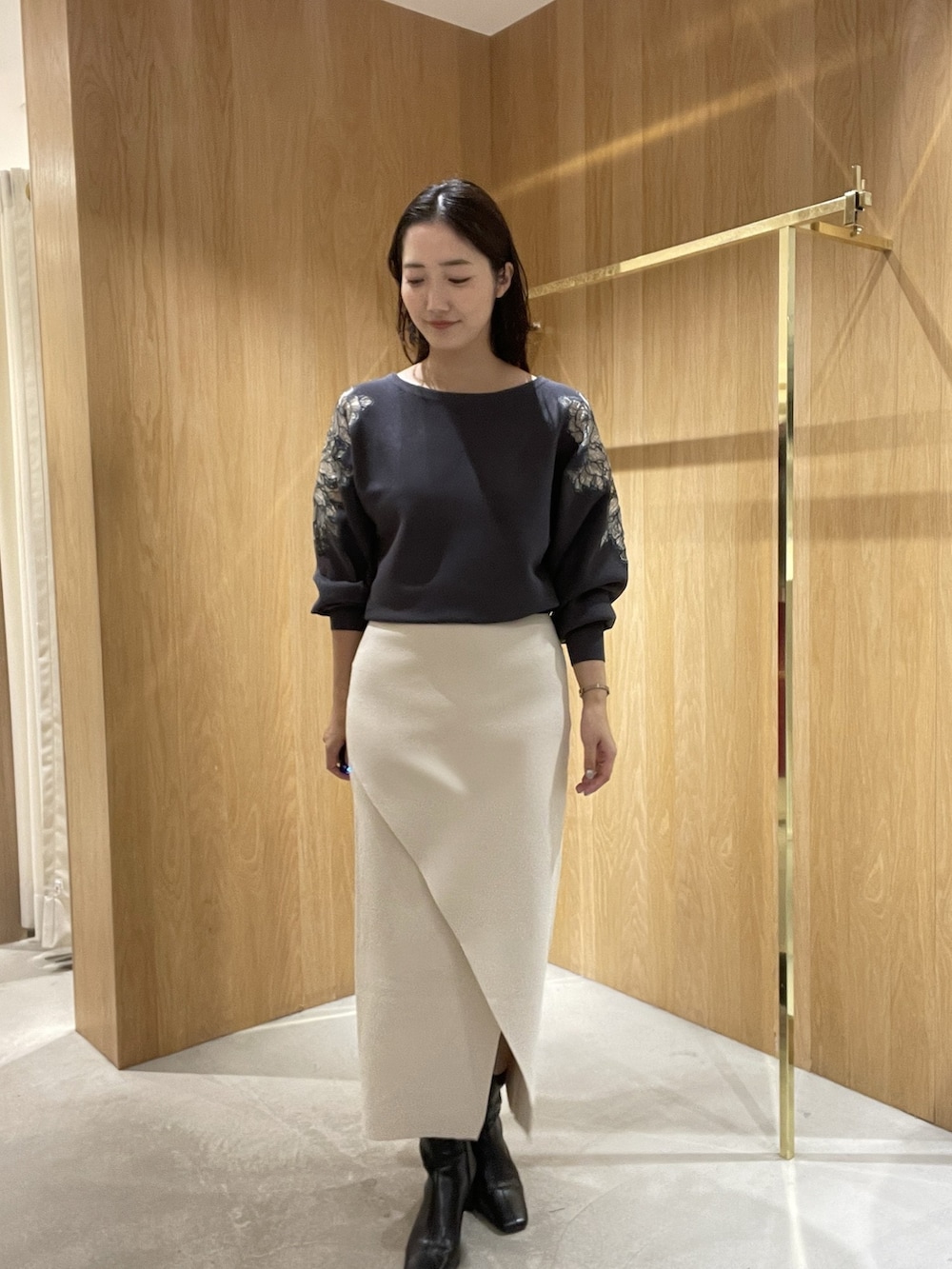 ホワイト系のスカート、グレー系のニット/セーター、ブラック系のブーツを着用したレディースの秋コーディネートの2枚目の写真