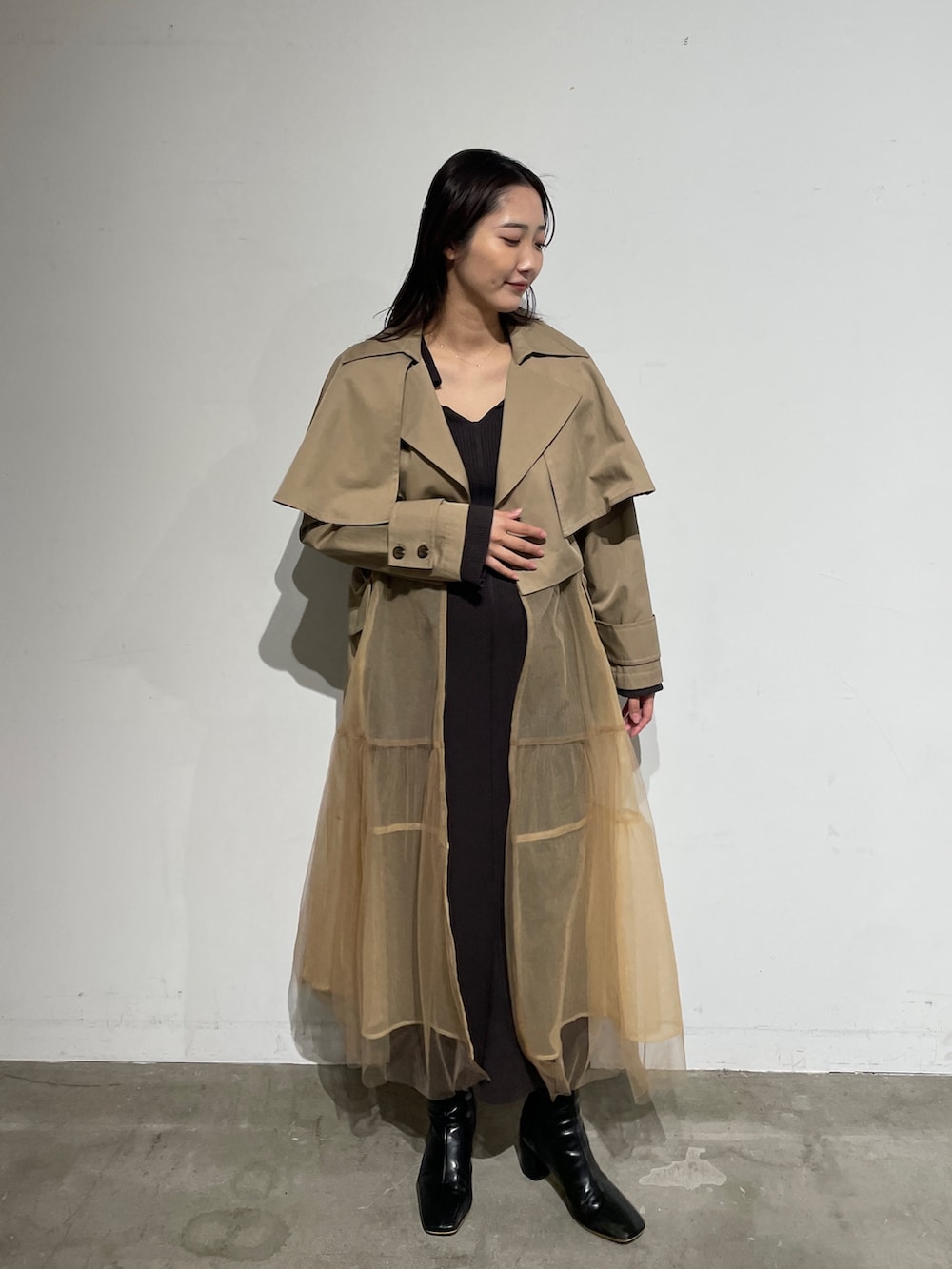 ブラック系のブーツ、グレー系のワンピース、ベージュ系のトレンチコートを着用したレディースの春コーディネートの3枚目の写真