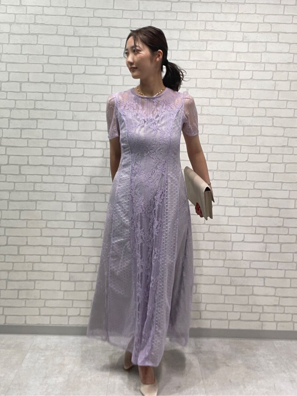 ベージュ系のパンプス、パープル系のドレス、ゴールド系のネックレスを着用したレディースの春コーディネートの2枚目の写真