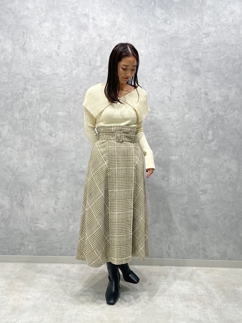 ブラック系のブーツ、ベージュ系のスカート、ホワイト系のニット/セーターを着用したレディースの秋コーディネートの3枚目の写真