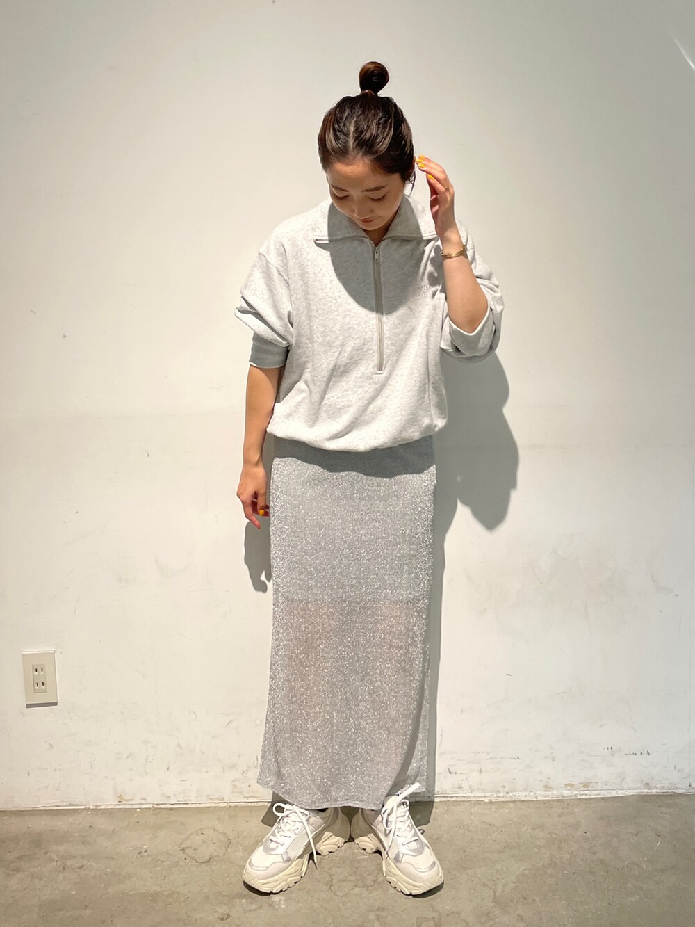 シルバー系のスカート、グレー系のスウェット、ホワイト系のスニーカーを着用したレディースの秋コーディネートの2枚目の写真
