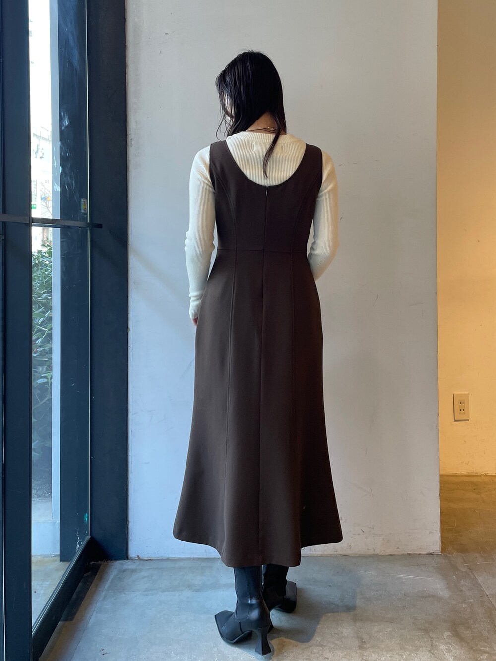 ブラック系のブーツ、ホワイト系のニット/セーター、ブラウン系のジャンパースカートを着用したレディースの冬コーディネートの5枚目の写真