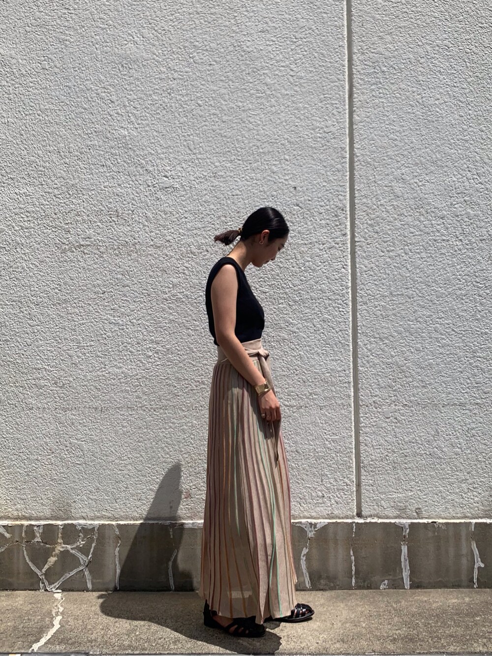 ベージュ系のスカート、ブラック系のニット/セーター、ゴールド系のバングル/リストバンドを着用したレディースの春コーディネートの2枚目の写真