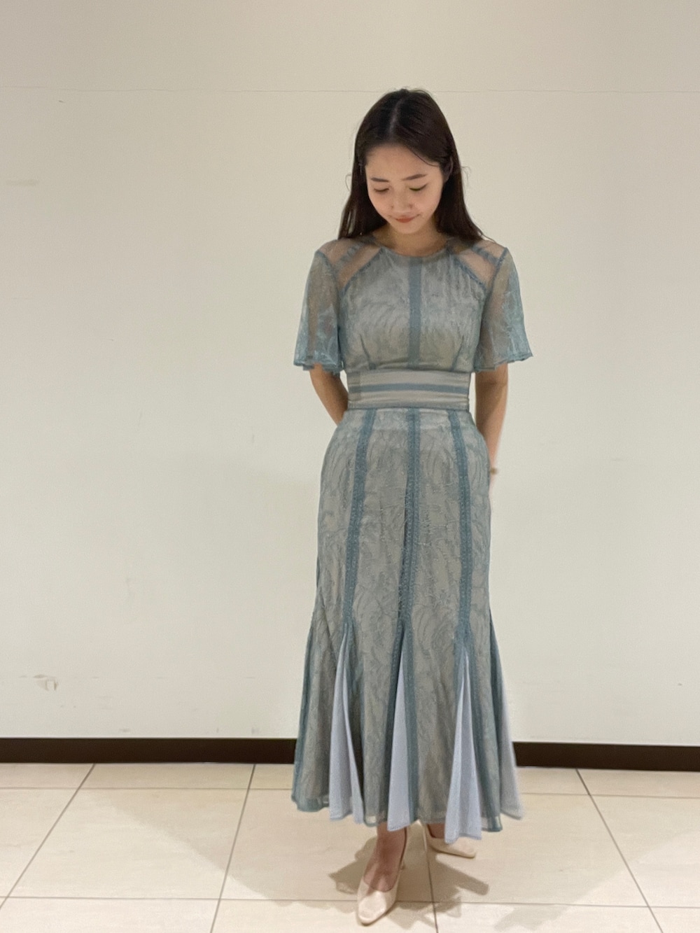 グリーン系のドレス、ベージュ系のパンプスを着用したレディースの春コーディネートの2枚目の写真